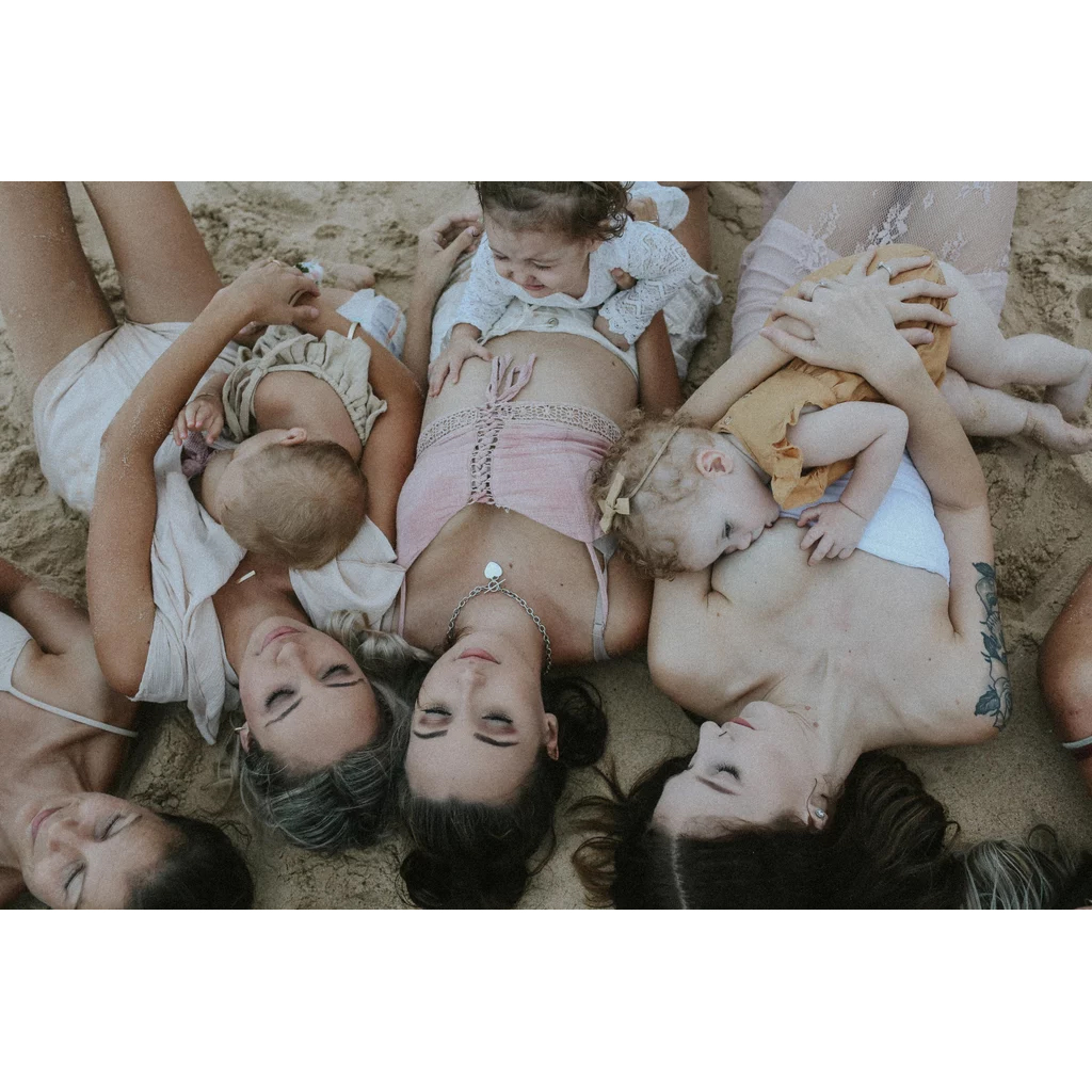 Celebrate body positivity and motherhood with stunning beach photographs that capture mothers in their natural beauty, breastfeeding their children while embracing their nakedness.